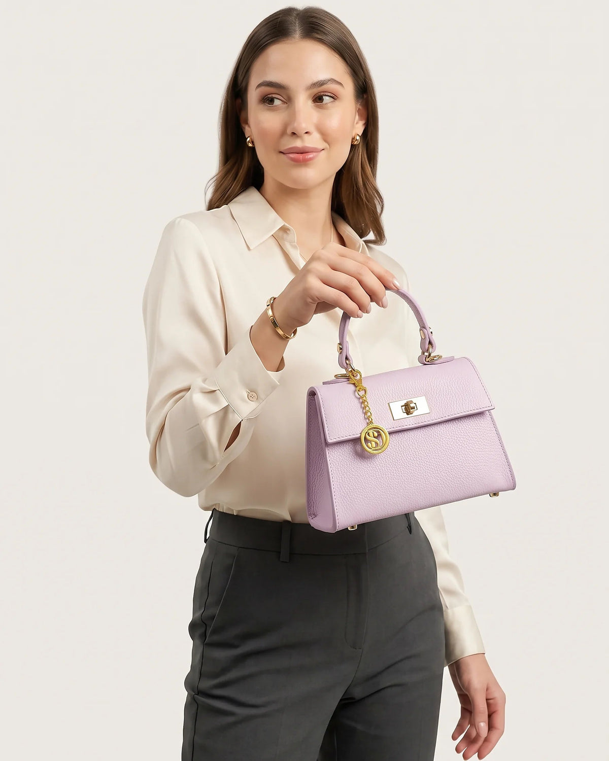 Donna che tiene in mano una mini borsa a mano in pelle nera su sfondo bianco